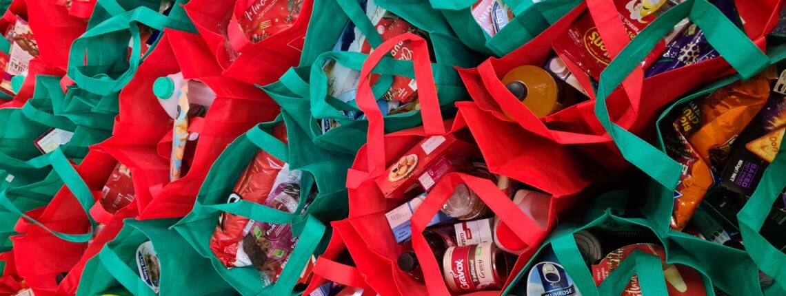 Dozens of red and green tote bags full of groceries and lined up.