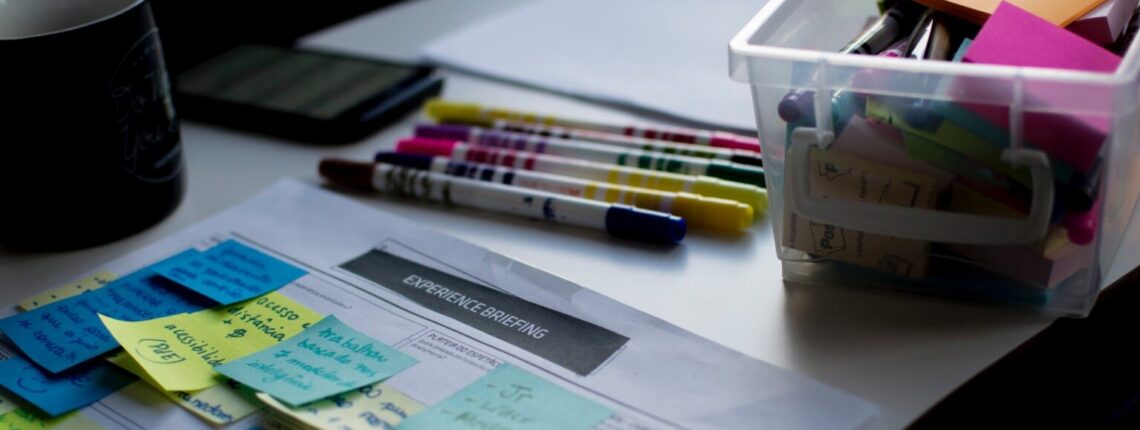 a desk with calendar, sticky notes, and a variety of colored pencils.