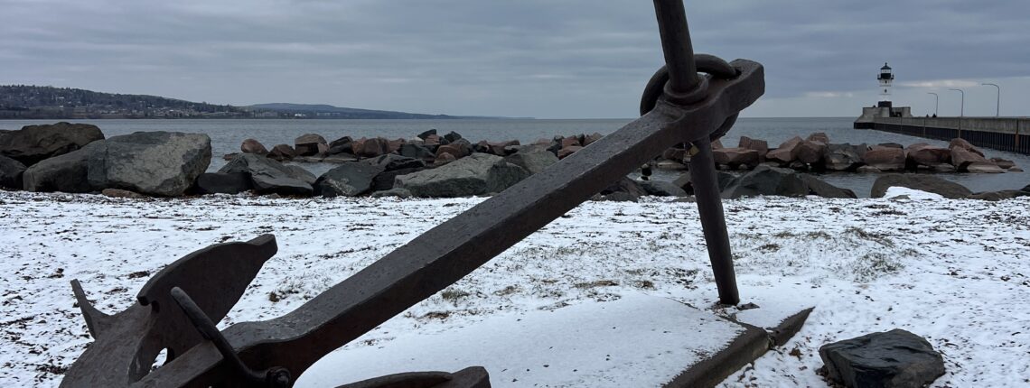 A ship's anchor on shore, on display.